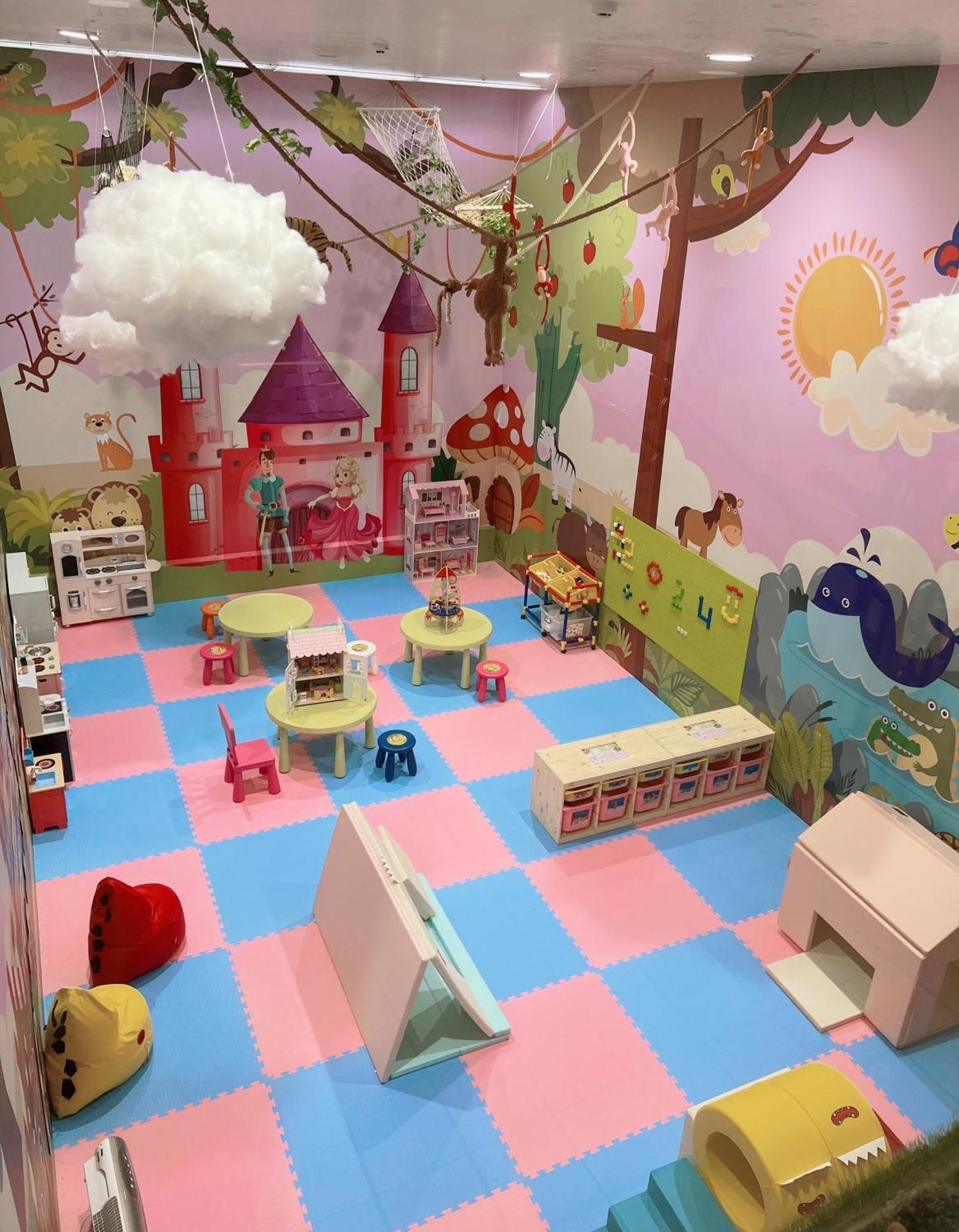 Evergreen Laurel Hotel - Taizhong Zewnętrze zdjęcie The photo shows a colorful playroom designed for children. It features a vibrant mural with a fairytale castle, trees, and playful animals on the walls. The floor is covered with interlocking foam tiles in pink and blue, providing a soft play surface