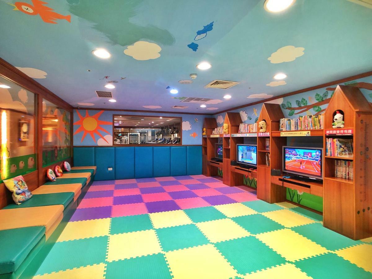 Evergreen Laurel Hotel - Taizhong Zewnętrze zdjęcie The photo shows a brightly colored children's playroom or activity area. The floor is covered with large colorful tiles in shades of blue, green, yellow, and pink, creating a playful pattern. The walls have cheerful decorations, including sun and clo