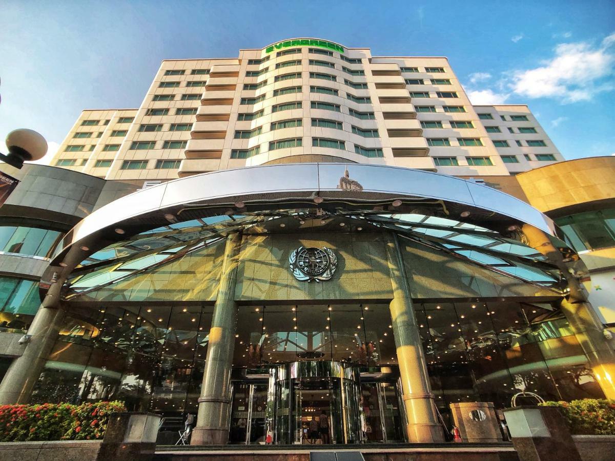 Evergreen Laurel Hotel - Taizhong Zewnętrze zdjęcie The photo shows the exterior of a modern hotel building. The entrance features a large, glass canopy supported by columns, creating a welcoming area. The facade of the hotel is composed of a mix of glass and concrete, with large windows that suggest 