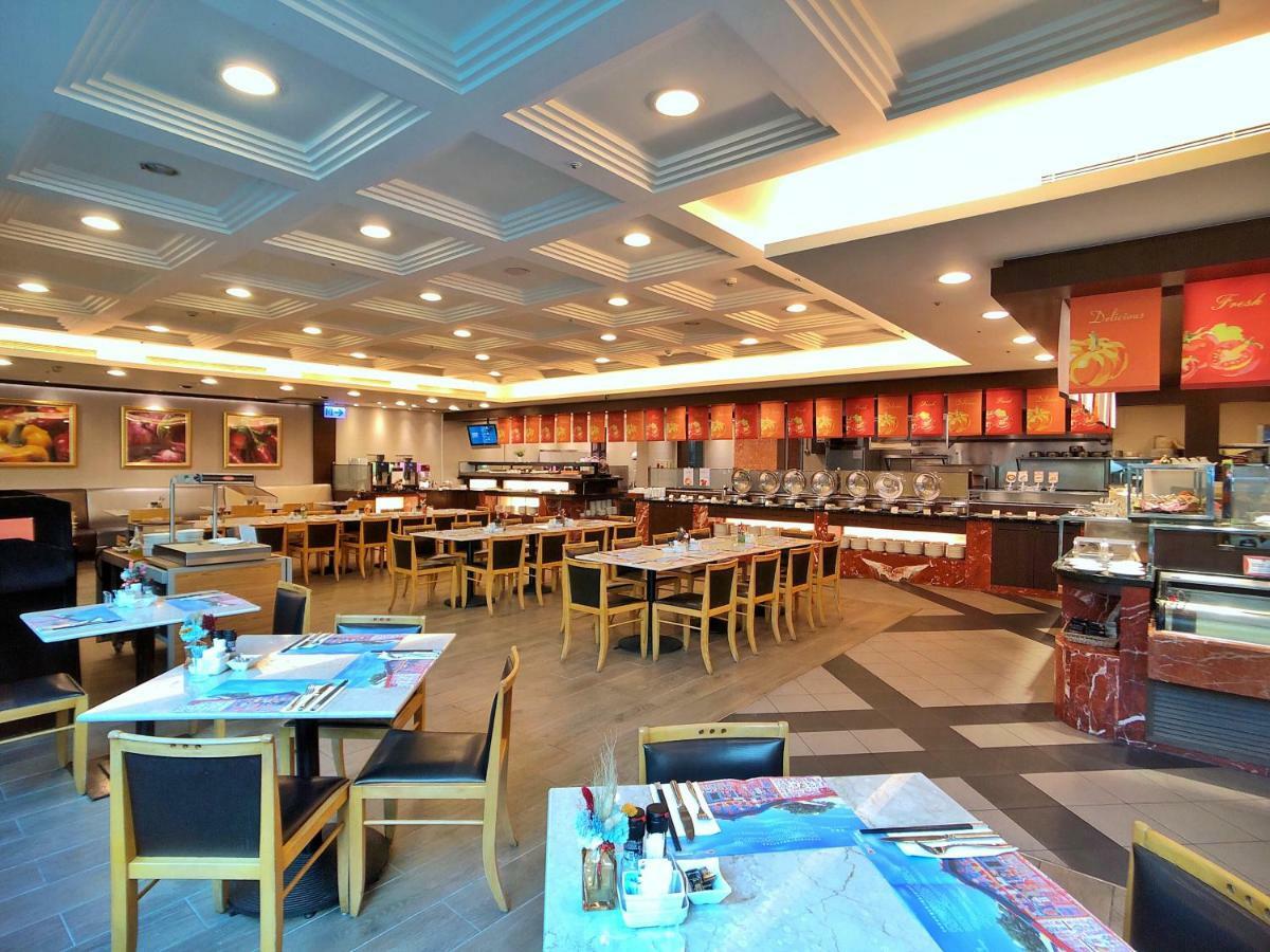 Evergreen Laurel Hotel - Taizhong Zewnętrze zdjęcie The photo shows the interior of a restaurant. The dining area features several tables with chairs arranged neatly. The flooring has a contemporary design, and the ceiling is structured with a coffered pattern. There is a buffet area along one wall wi