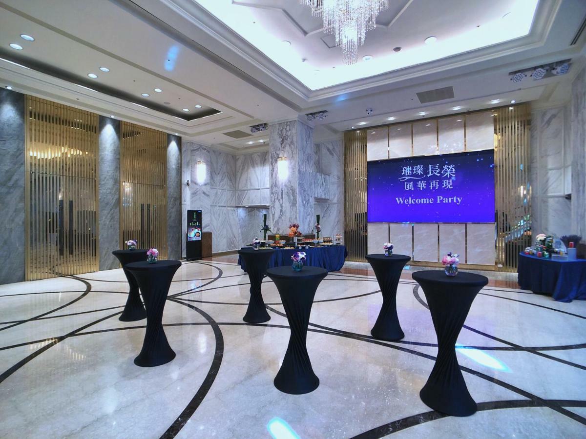 Evergreen Laurel Hotel - Taizhong Zewnętrze zdjęcie The photo depicts a spacious and elegantly decorated event space, likely set up for a welcome party. The room features polished marble flooring and tall ceilings, giving it a sophisticated atmosphere. In the center, several round tables with black ta