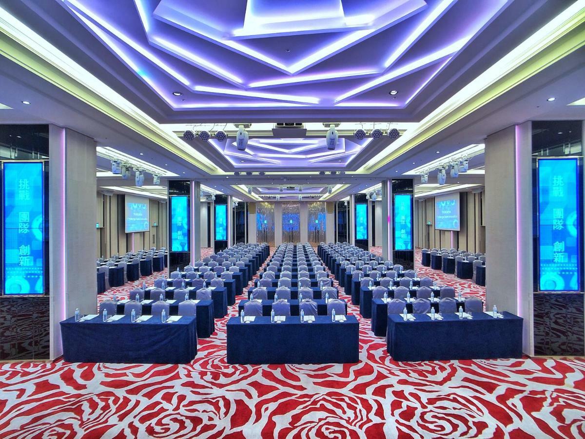 Evergreen Laurel Hotel - Taizhong Zewnętrze zdjęcie The photo shows a large conference or seminar room set up for an event. The space features rows of tables and chairs arranged neatly, likely for attendees to participate in discussions or presentations. The room is well-lit with modern, colorful ligh