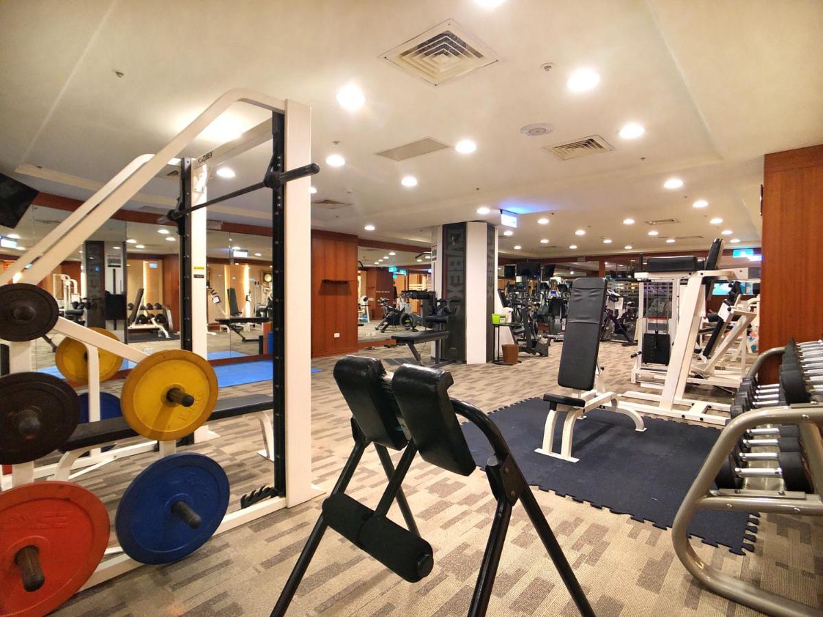 Evergreen Laurel Hotel - Taizhong Zewnętrze zdjęcie The photo shows a gym interior with various workout equipment. On the left, there are weights of different colors stacked on a weight rack. In the foreground, there's a bench for exercises, and in the background, multiple machines for strength traini